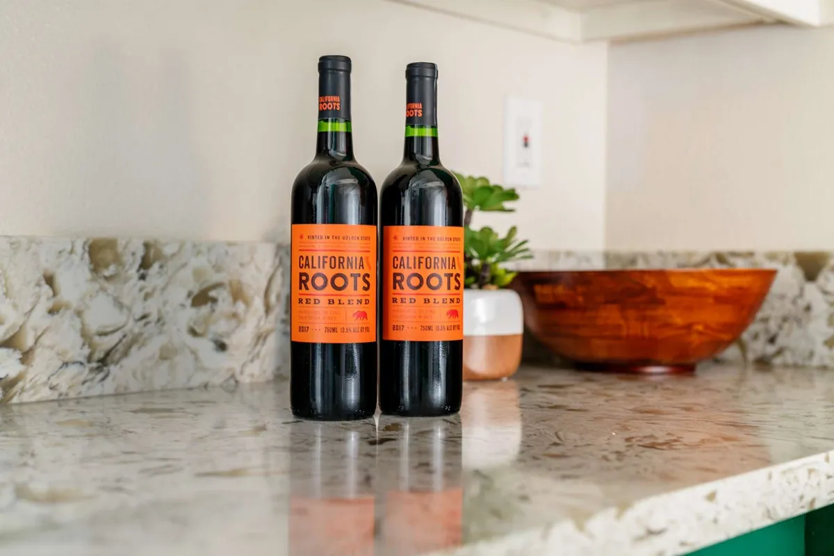 A close-up shot of a kitchen countertop displays two bottles of wine and a wooden bowl, suggesting a space perfect for sharing drinks and preparing meals. The setting exudes a relaxed and welcoming atmosphere, ideal for gatherings and entertaining guests.