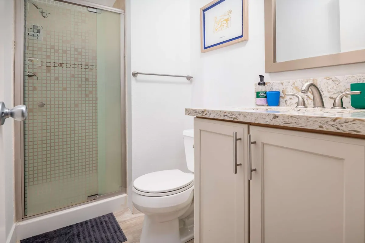 A serene bathroom scene focusing on the spacious shower area and a vanity with sink, complemented by framed artwork and a large mirror. The atmosphere is inviting and spa-like, ideal for both invigorating morning routines and unwinding after a busy day.